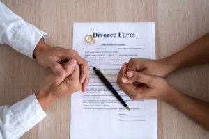 Couple mains jointes devant un formulaire de divorce à Chambéry avec alliances et stylo